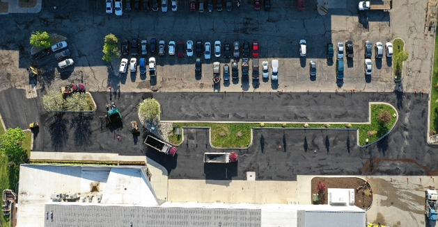 overhead shot of a parking lot midway through paving with various vehicles in it